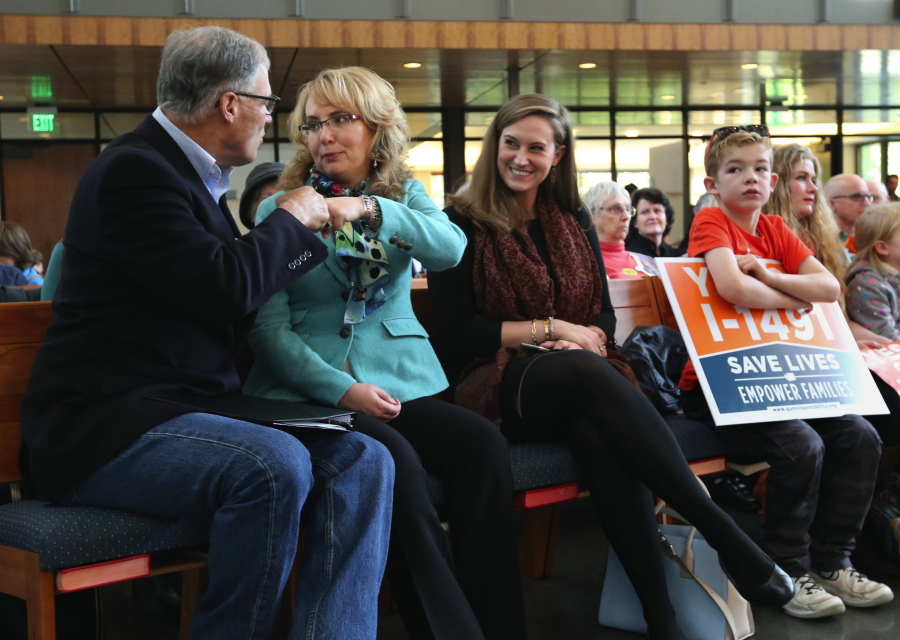 FILE - In this Oct. 22, 2016 file photo, former Arizona congresswoman Gabby Giffords, second from left, and Gov. Jay Inslee, left, fist bump at a rally in support of Initiative 1491 in Seattle. The initiative, which will be on the ballot in the November election, would would allow family members and law enforcement officials to petition a judge to temporarily suspend a person&#039;s access to firearms if the court finds that he is a threat to himself or others.