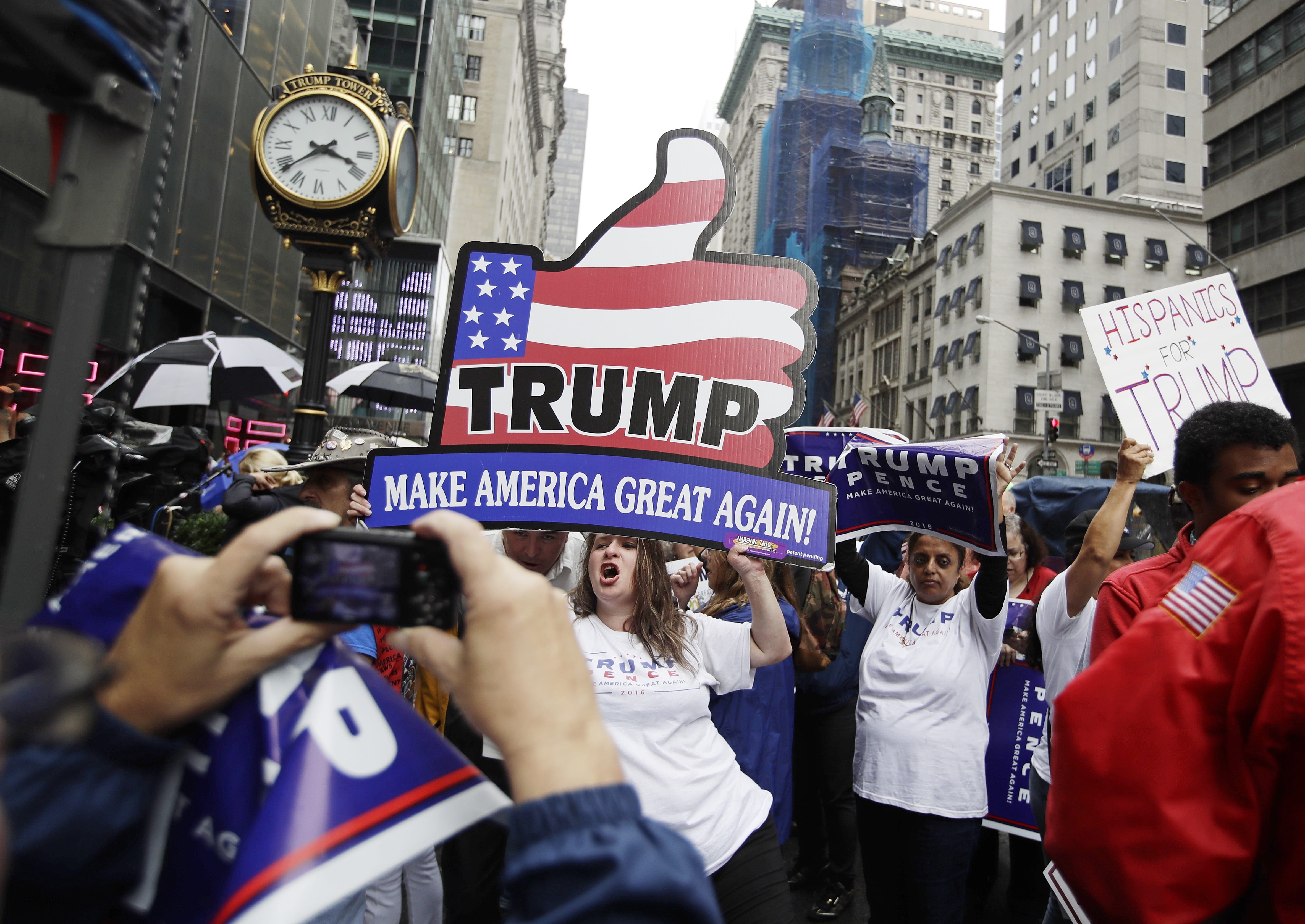 Supporters of Republican presidential nominee Donald Trump gather at Trump Tower Saturday, Oct. 8, 2016, in New York. Trump insisted Saturday, Oct. 8, 2016, he would "never" abandon his White House bid, facing an intensifying backlash from Republican leaders across the nation who called on him to quit the race following the release of his sexually charged comments caught on tape.