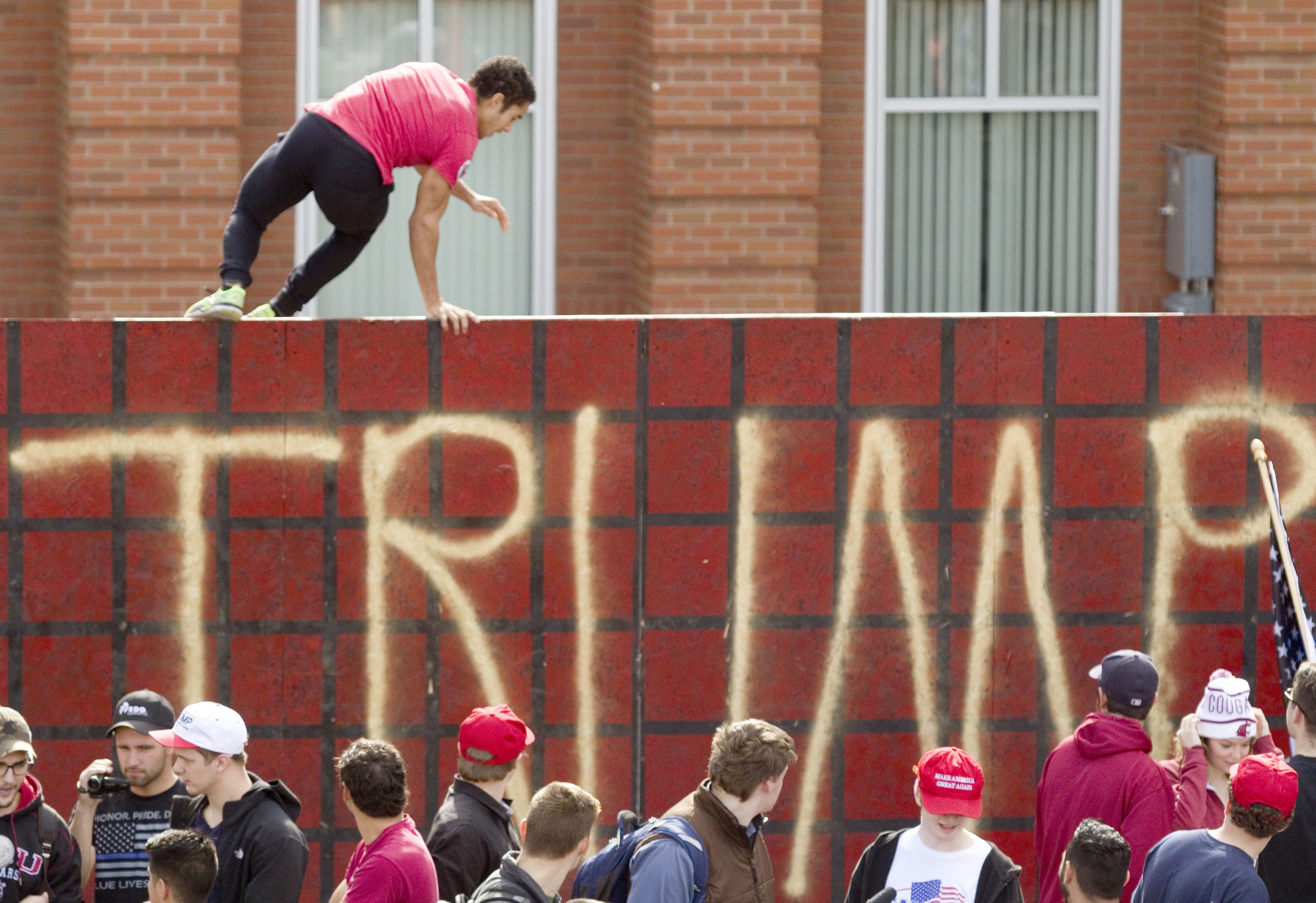 Counter-protester Demietrich Baker jumps over a Trump wall erected by the Washington State University College Republicans on campus on Wednesday, Oct. 19, 2016, in Pullman, Wash. Baker said he was trying to demonstrate that a wall along the country's souther border would be dehumanizing and wouldn't stop illegal immigration. The wall was erected in support of Donald Trump's proposal to build a wall along the border with Mexico.