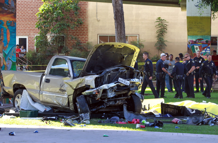 Police stand near the pickup truck that landed at Chicano Park after it flew off a ramp to the San Diego Coronado Bridge in San Diego on Saturday.