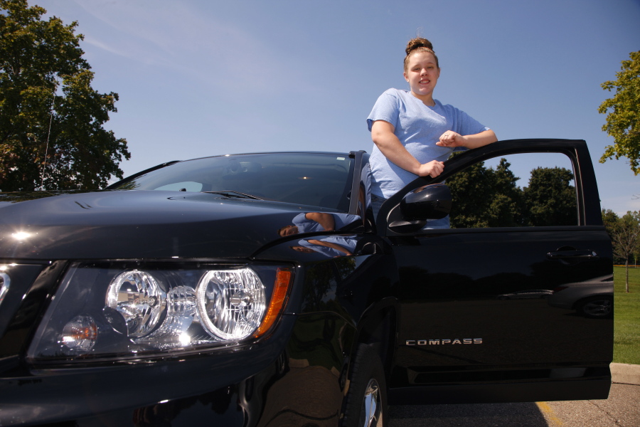 In this Friday, Aug. 26, 2016, photo, Alaina Dishman poses with her new Jeep Compass, in Delta Township, Mich., near Lansing. Dishman was among those who didn???t have enough credit to buy a new car when she went to a showroom last summer. But a salesman got her into a program that helps young people build credit.