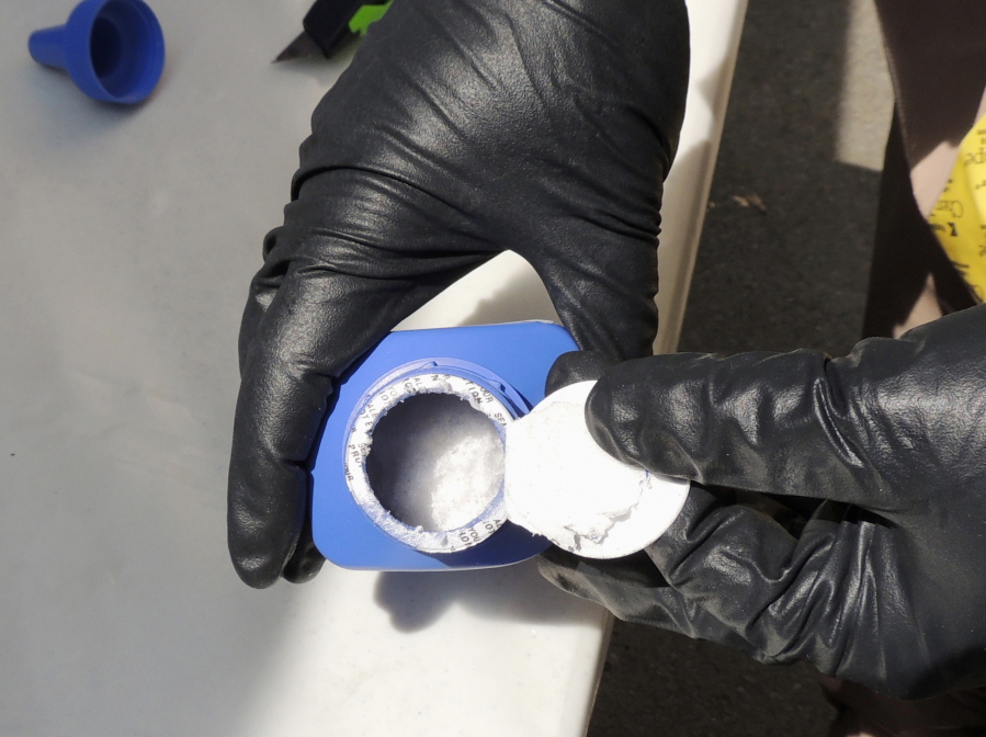 A member of the RCMP opens a printer ink bottle containing the opioid carfentanil imported from China, in Vancouver. Drug dealers have been cutting carfentanil and its weaker cousin, fentanyl, into heroin and other illicit drugs to boost profit margins.