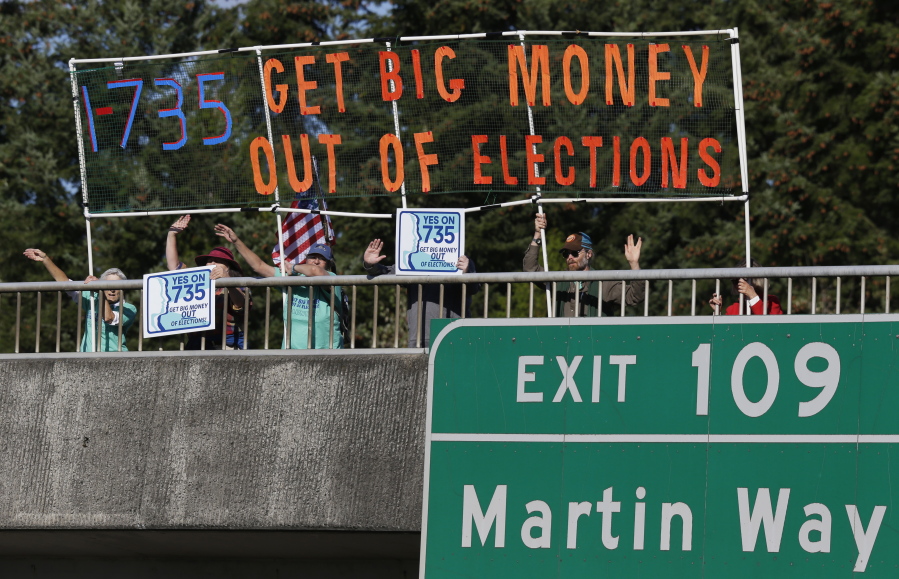 Supporters of Initiative 735 hold a banner Sept. 22 above Interstate 5 during the evening commute in Lacey. Proponents of the statewide ballot initiative want to get big money out of politics by backing a federal constitutional amendment that says free speech in the form of political contributions belongs to people, not corporations. Opponents of the measure say the government shouldn&#039;t limit the First Amendment. (AP Photo/Ted S.