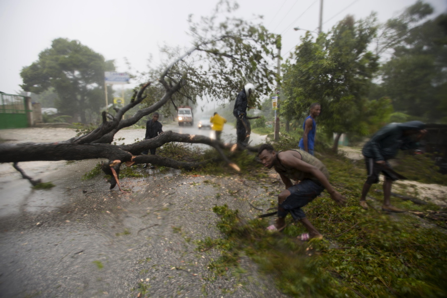 People work to remove an uprooted tree from a road Tuesday in Leogane, Haiti. Hurricane Matthew slammed into Haiti&#039;s southwestern tip with howling, 145 mph winds Tuesday, tearing off roofs in the poor and largely rural area, uprooting trees and leaving rivers bloated and choked with debris.