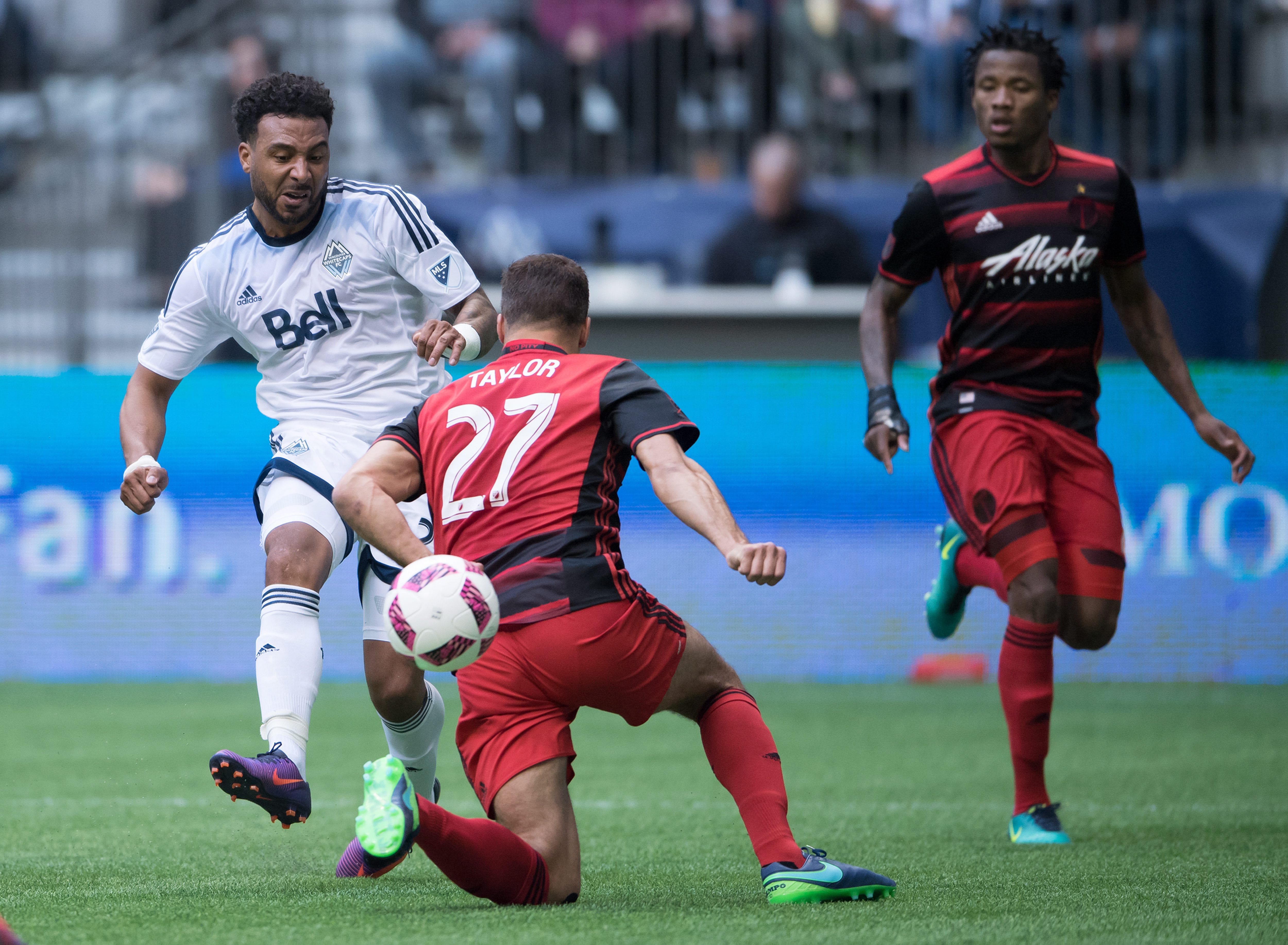 Vancouver Whitecaps' Giles Barnes, left, puts the ball past Portland Timbers' Steven Taylor (27) and scores a goal as Alvas Powell, right, watches during the first half of an MLS soccer game in Vancouver, British Columbia, on Sunday Oct. 23, 2016.