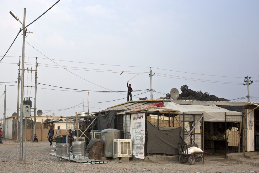 A boy plays with a rope as he stands atop a makeshift convenience store at a camp for displaced families in Dibaga, near Mosul, Iraq, on Monday. The campaign to retake Mosul comes after months of planning and involves more than 25,000 Iraqi troops, Kurdish forces, Sunni tribal fighters and state-sanctioned Shiite militias.