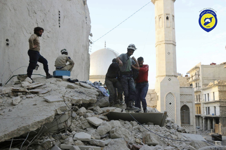 Civil Defense workers from the White Helmets carry a victim Tuesday as they walk on the rubble of a destroyed building after airstrikes hit the Bustan al-Basha neighborhood in Aleppo, Syria.