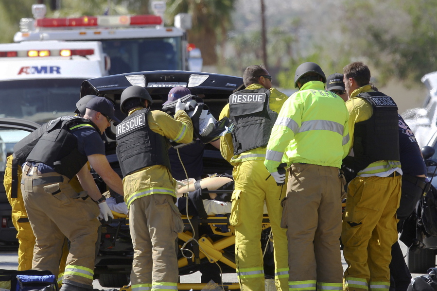 Emergency personnel wearing bullet-proof vests tend to a person on a stretcher Saturday in Palm Springs, Calif.