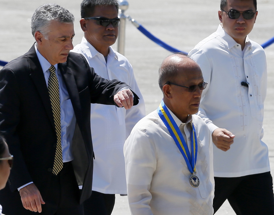Outgoing U.S. Ambassador to the Philippines Philip Goldberg, left, looks at his watch as he follows Philippine Defense Secretary Delfin Lorenzana, second from right, following the formal turnover of the Philippine Air Force C-130T cargo plane, the second to be acquired through the United States Excess Defense Articles at Villamor Air Base in suburban Pasay city south of Manila, Philippines, on Monday.