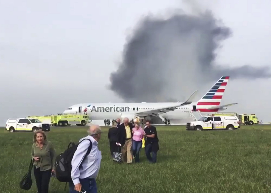 In this photo provided by passenger Jose Castillo, fellow passengers walk away from a burning American Airlines jet that  caught fire on the runway Friday at Chicago&#039;s O&#039;Hare International Airport.