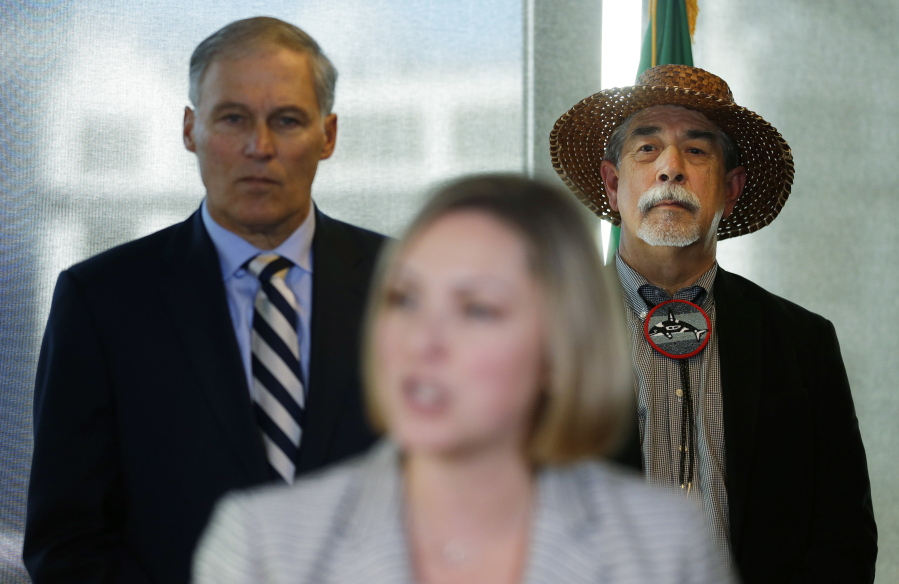 Gov. Jay Inslee, left, and Mel Sheldon Jr., chairman of the Tulalip Tribe, listen to Christy Goldfuss, managing director of the White House Council on Environmental Quality, speak Tuesday at a press conference in Seattle. (Ted S.