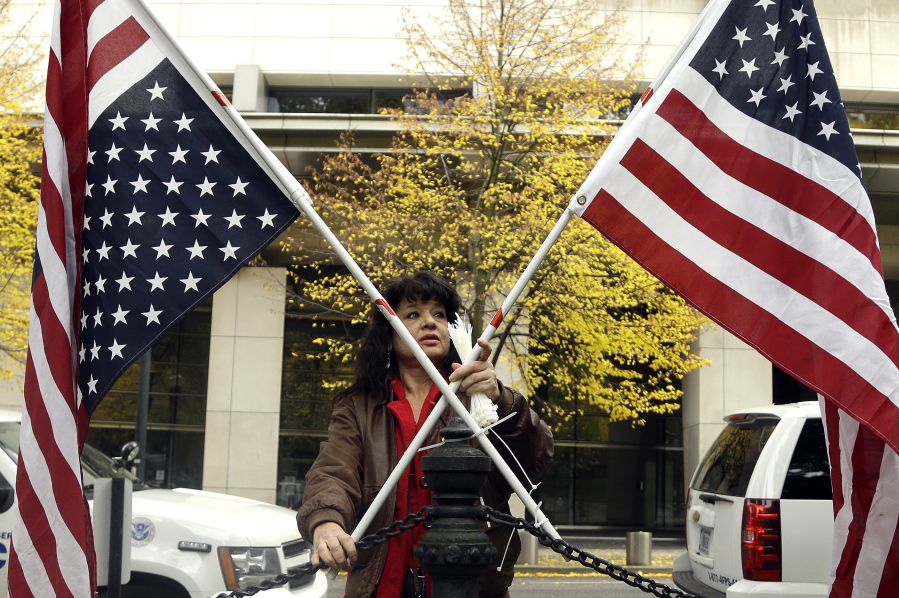 Maureen Valdez attaches crossed American flags to a fence post Tuesday outside the federal courthouse in Portland. A handful of supporters have gathered outside the courthouse as a jury deliberates on the fate of seven defendants involved with the armed occupation of a national wildlife refuge in Eastern Oregon this year.