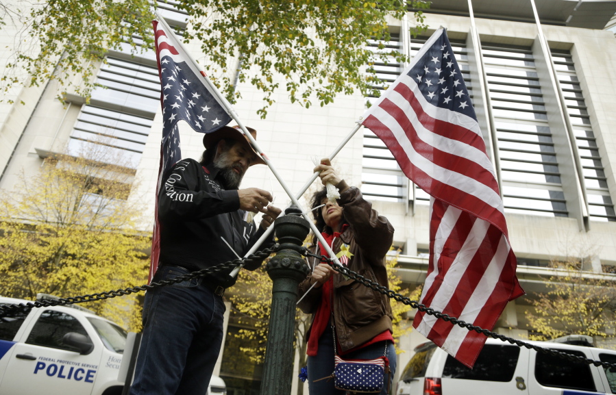 Maureen Valdez, right, and David Brugger attach crossed American flags to a rail post outside the federal courthouse in Portland on Tuesday. A handful of supporters have gathered outside the courthouse as a jury continues to deliberate on the fate of seven defendants involved with the armed occupation of a national wildlife refuge in central Oregon earlier this year.