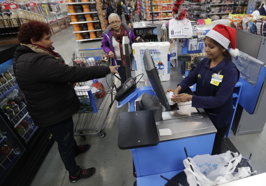 Gladys Ortega, left, and Ursula Polano, center, both from Paterson, N.J., check out at the register of Dimpal Mandania, at Wal-Mart in Teterboro, N.J. Wal-Mart may be known for its everyday low prices, but this holiday season it wants to be known for service, too.