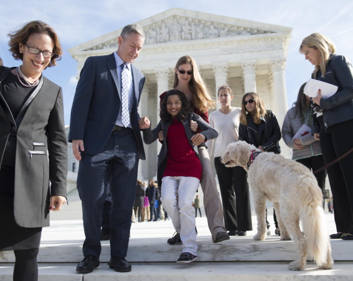 Ehlena Fry, 12, is helped down the steps of the Supreme Court in Washington on Monday by her mother, Stacy Fry, and Michael J. Steinberg, ACLU of Michigan Legal director, and dog Wonder, following oral arguments in Fry&#039;s case who has cerebral palsy who, at age 5, was banned from bringing her service dog, Wonder, to class.