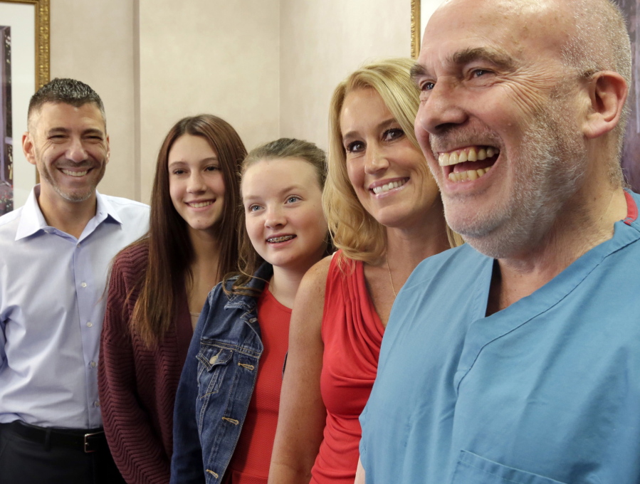 From left, Peter Foster, daughters, Emma and Kerry; wife, Susan Foster, and embryologist Dr. Jacques Cohen pose for a photograph at St. Barnabas Hospital, in Livingston, N.J., on Tuesday. More than 15 years ago, 17 babies, including Emma, were born after an experimental infertility treatment that gave them DNA from three people: Mom, Dad and an egg donor. Now researchers have checked up on how the babies are doing as teenagers. The preliminary verdict: The kids are all right.