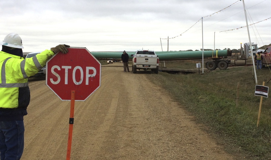 A crew member stops traffic as work resumed Tuesday, Oct. 11, 2016, on the four-state Dakota Access pipeline near St. Anthony, N.D. A federal appeals court ruling on Sunday cleared the way for work to resume on private land.