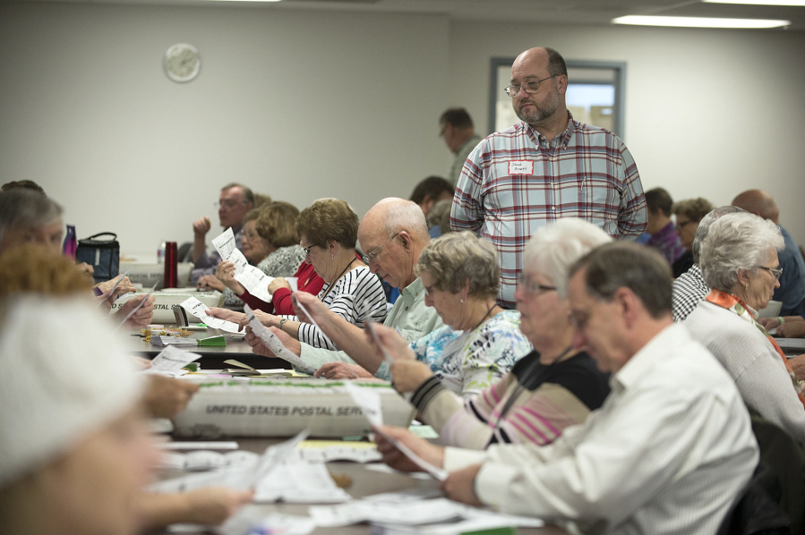 Republican observer David Arnett, standing, keeps an eye on the process at the Clark County Department of Elections on Wednesday afternoon.