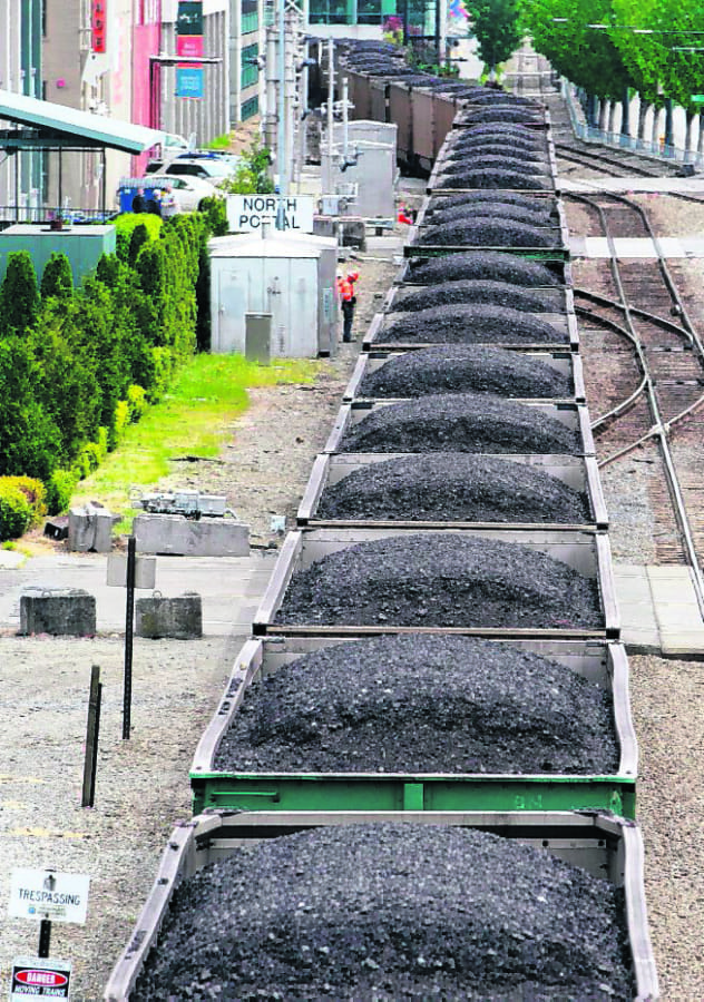 A train hauling coal heads north out of Seattle in 2012 between office buildings, condos and the downtown waterfront.