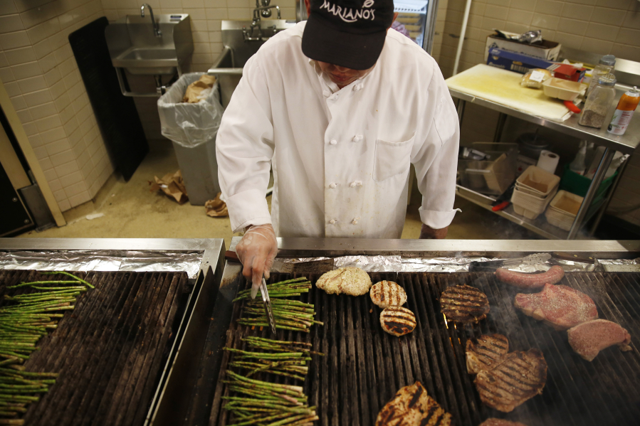 Jose Vilchez mans the grill area at a Chicago Mariano&#039;s store in 2015. Grocery stores have ramped up their prepared food options in recent years but have kept their prices steady.