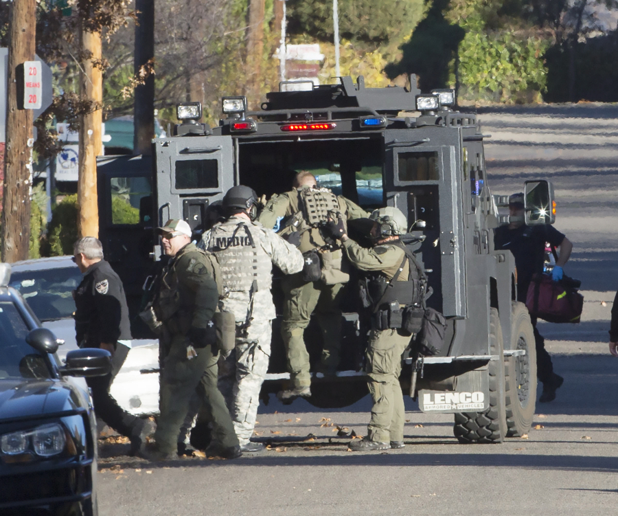 A policeman injured in a shootout is helped into a tactical armored vehicle on Friday, Nov. 11, 2016, after a fugitive was discovered in an alley along Irving Street in Boise, Idaho.