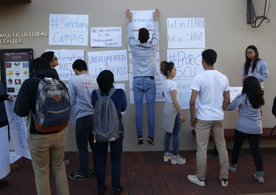 Santa Clara University students hang signs Nov. 17 outside of Shapell Lounge after participating in a walk-out in support of the undocumented community at Santa Clara University in Santa Clara, Calif. (Nhat V.