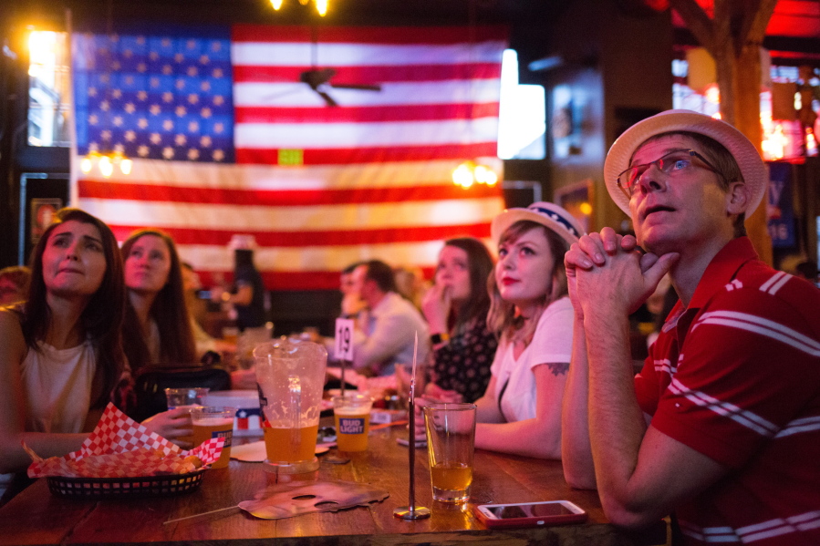 People watch returns trickle in during an election night watch party Tuesday at The Comet Tavern in Seattle.