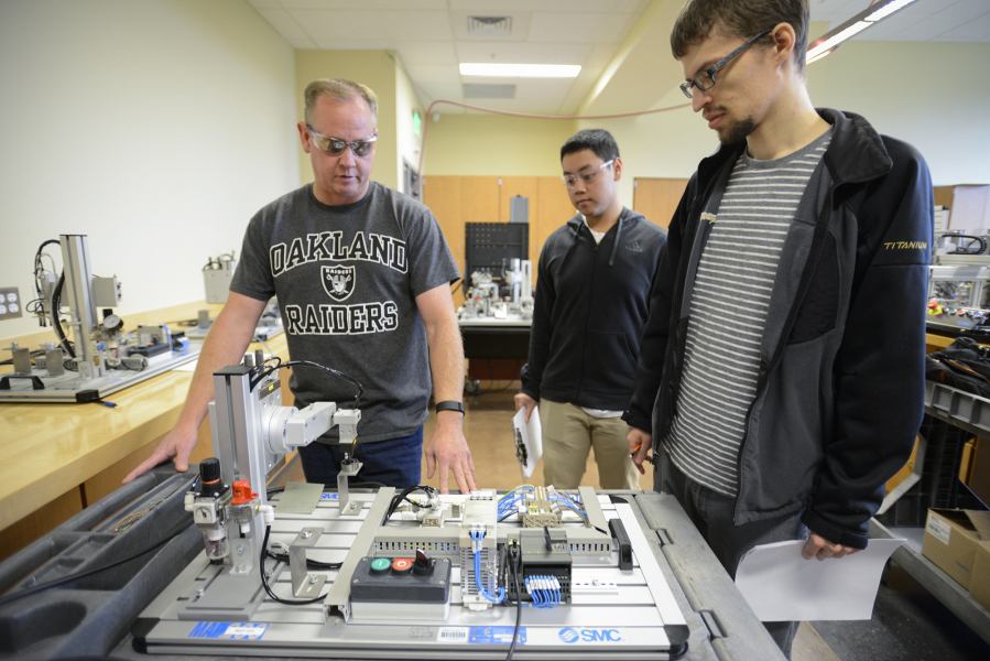 From left to right, students David Gullickson, Toby Sabandith and Bruce Gates, test a pick-and-place robot during their mechatronics class at Clark College in Vancouver on Wednesday. Clark College is tailoring its advanced manufacturing programs to better meet the needs of local companies.