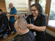 Mobile barber Marty Brusco cuts the hair of Army veteran Frank Lofting on Wednesday afternoon at the Vancouver VA Medical Center.