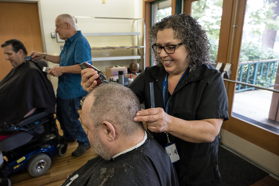 Mobile barber Marty Brusco cuts the hair of Army veteran Frank Lofting on Wednesday afternoon at the Vancouver VA Medical Center.