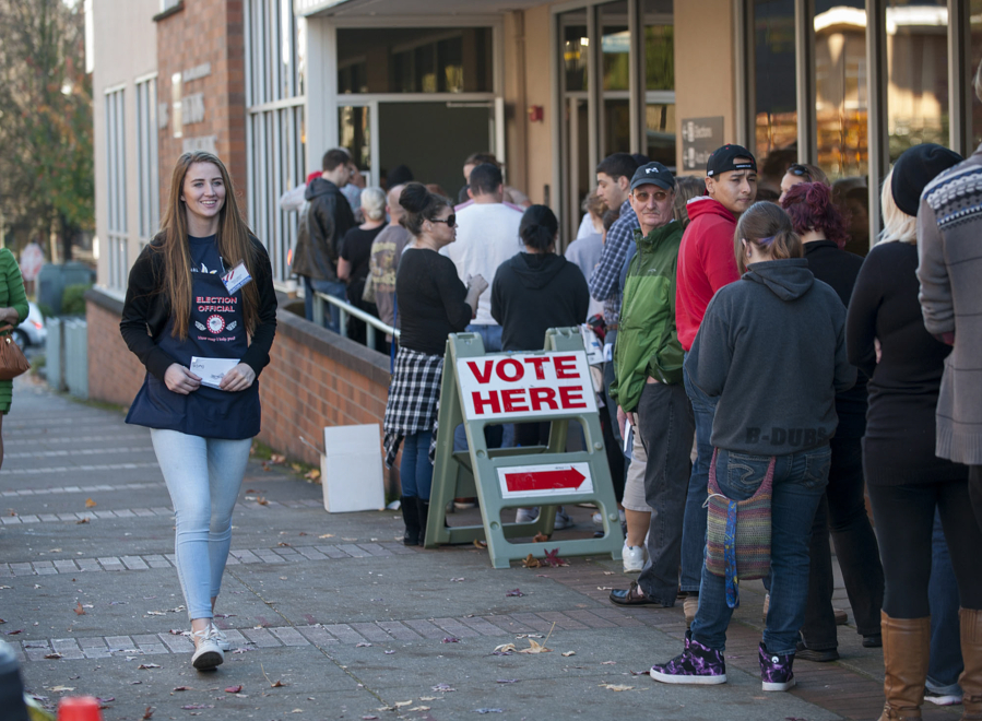 Skyview High School senior Ashlee Comastro, 17, left, a member of the National Honor Society, assists voters outside the Clark County Elections Office on Tuesday afternoon.
