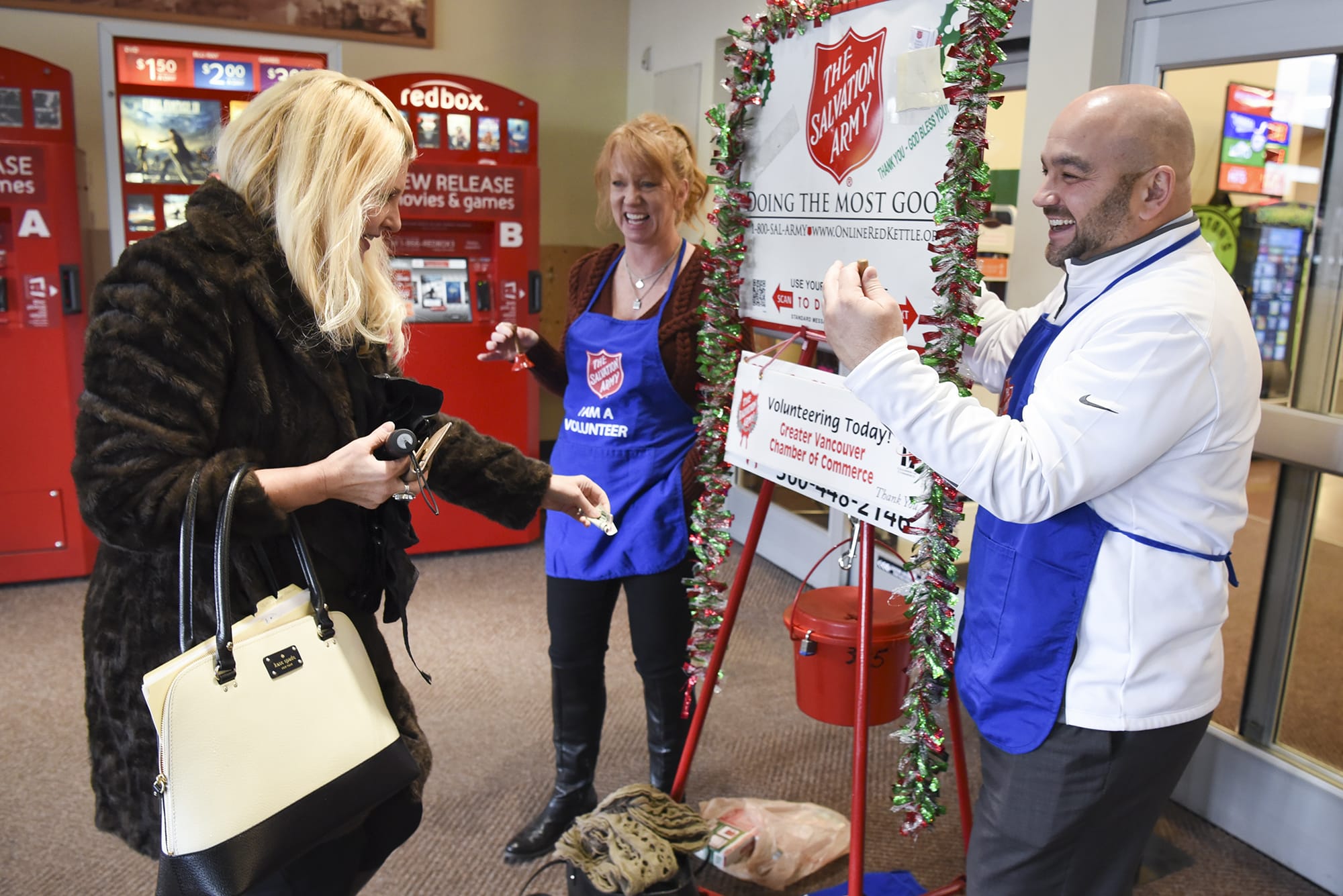 Carol Bua, left, donates spare change to Salvation Army bell ringers, Amy Ohara, center, and Eric Sawyer, who are on the Board of Directors for the Greater Vancouver Chamber of Commerce, Wednesday November 30, 2016 at the Grand Central Station Fred Meyer.