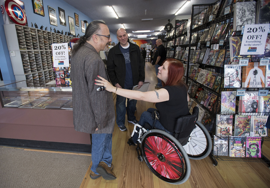 Illustrator Rebecca Woods speaks with Steve Borock, the president of the Comic Book Certification Service, who was among the industry workers Friday who helped raise money for the Battle Ground woman&#039;s new wheelchair at Vancouver&#039;s I Like Comics.