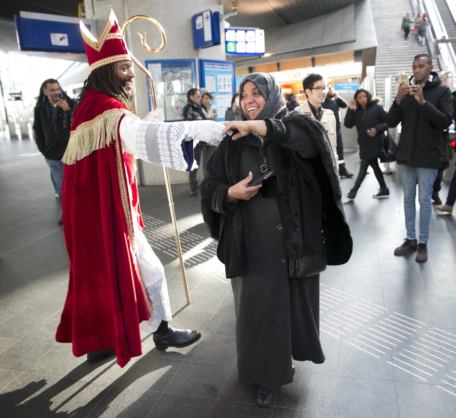 Sinterklaas, traditionally played by a white person, dances with a Muslim woman at subway station in Amsterdam, Netherlands, Saturday, Nov. 5, 2016. The steam boat carrying Sinterklaas, the Dutch equivalent of Santa Claus is not due to chug into the historic harbor of Maassluis until next weekend, but the annual polarized debate about his helper &quot;Black Pete&quot; has been underway for weeks.
