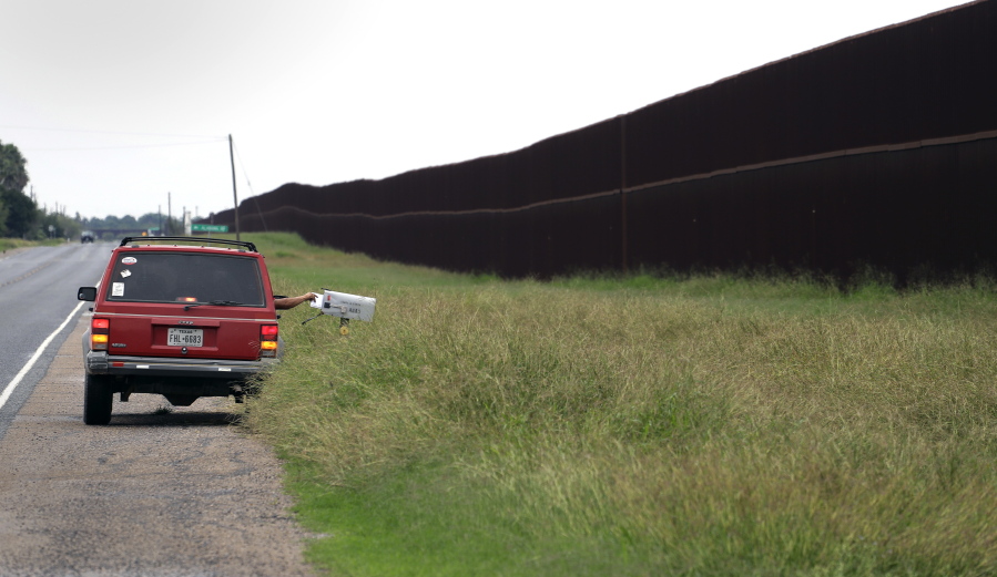 A carrier delivers mail along a section of border fence in Brownsville, Texas. The idea of a concrete wall spanning the entire 1,954-mile southwest frontier collides head-on with multiple realities, like a looping Rio Grande, fierce local resistance, and cost.