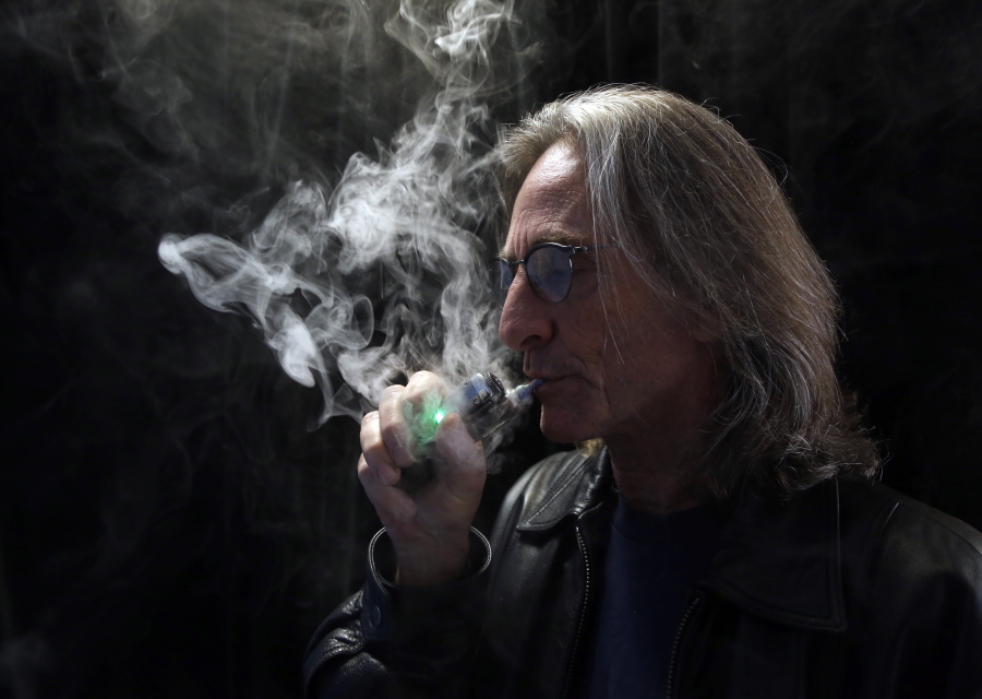 John Hartigan, proprietor of Vapeology LA, a store selling electronic cigarettes and related items, takes a puff of an electronic cigarette Dec. 4, 2013, at his store in Los Angeles. As smoking declines nationwide, states are increasingly turning to taxing electronic cigarettes, a trend that concerns some public health experts who fear it could deter smokers from switching to the potentially safer alternative. California became the seventh state to tax e-cigarettes after voters overwhelmingly approved a ballot measure Nov. 8, 2016.