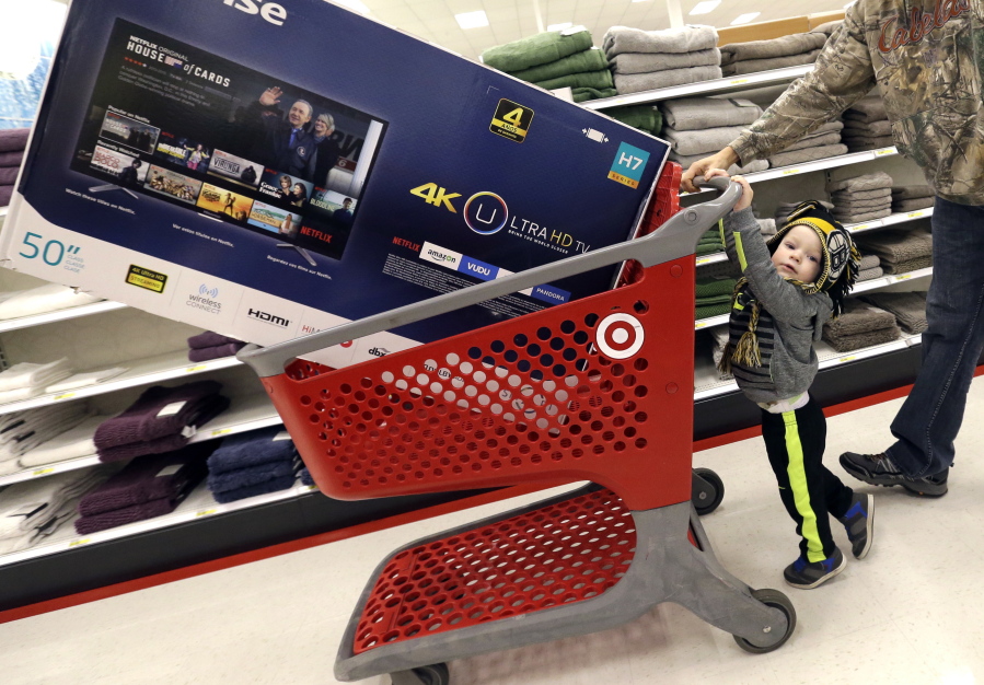 FILE - In this Friday, Nov. 25, 2016, file photo, Hunter Harvey, 2, helps his dad, C.J., wheel a big screen TV at Target, in Wilmington, Mass.   On Tuesday, Nov. 29, the Commerce Department reports the second of three estimates for the third quarter on the U.S. gross domestic product.