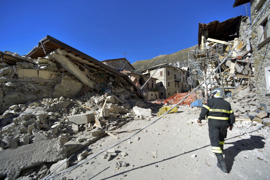 A firefighter walks past rubble Tuesday in the village of Pretare, Italy. Earthquake aftershocks gave central Italy no respite on Tuesday, haunting a region where thousands of people were left homeless and frightened by a massive weekend tremor.