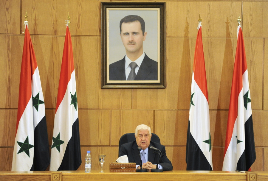 Walid al-Moallem sits beneath a portrait of Syrian President Bashar Assad as he speaks during a press conference in Damascus, Syria, Sunday, Nov. 20, 2016. The Syrian government on Sunday refused a U.N. proposal to grant the rebel-held eastern districts of Aleppo autonomy in order to restore calm to the war-torn city.