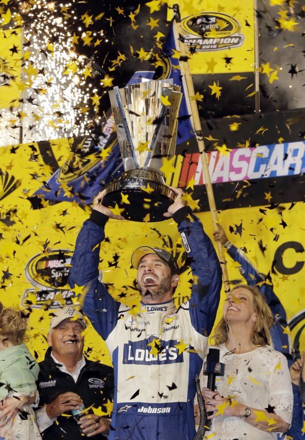 Jimmie Johnson lifts the trophy as he celebrates the NASCAR Sprint Cup auto race and series title, Sunday, Nov. 20, 2016, in Homestead, Fla.
