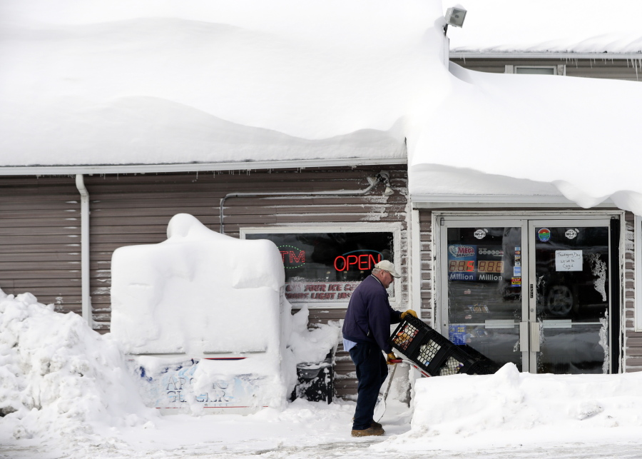 Bob Fox delivers milk to Grafton&#039;s Town Store, as he walks through lake-effect snow on the ground Monday in Grafton, N.Y.