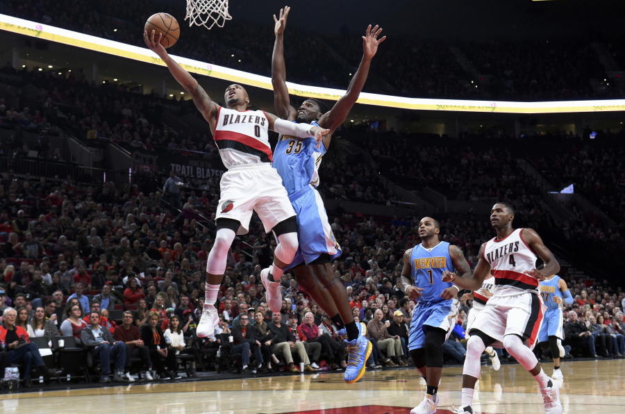 Portland Trail Blazers guard Damian Lillard drives to the basket and scores on Denver Nuggets forward Kenneth Faried during the third quarter of an NBA basketball game in Portland, Ore., Sunday, Nov. 13, 2016. The Blazers won 112-105.