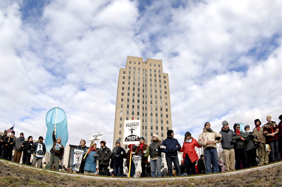 Dakota Pipeline protesters stand arm-in-arm in front of the state Capitol in Bismarck, N.D., before marching downtown to the William L. Guy Federal Building Monday.