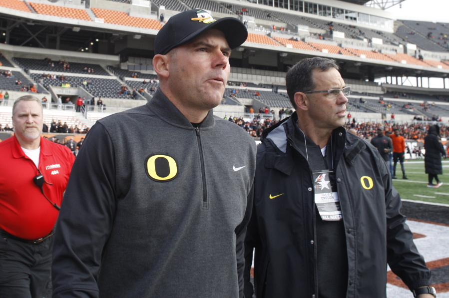 Oregon head coach Mark Helfrich, center, comes onto the field for an interview before an NCAA college football game against Oregon State, in Corvallis, Ore., Saturday Nov. 26, 2016. (AP Photo/Timothy J.