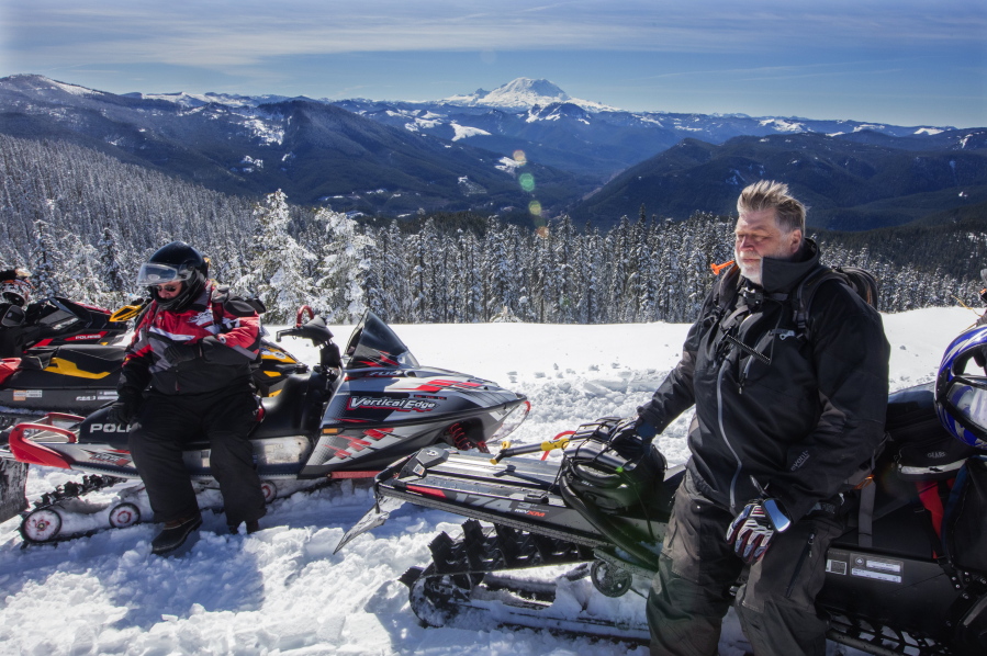 Bob Seelye and Mick Steinman sit on snowmobiles March 17 at the top viewpoint of the trail system near Crystal Springs Sno-Park, with their backs to Mount Rainier.