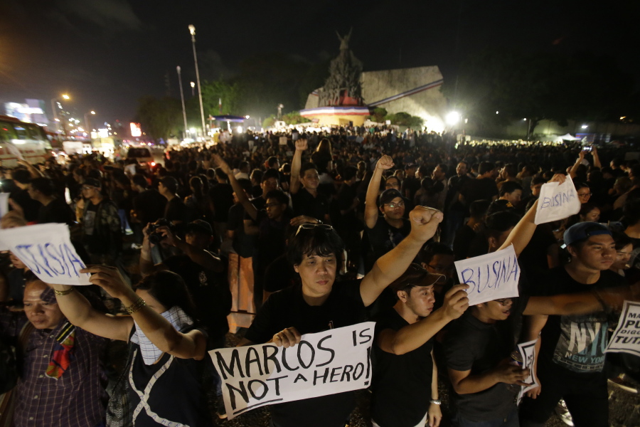 Filipinos hold slogans as protesters gather at the People&#039;s Power Monument in Quezon city, north of Manila Philippines on Friday to protest against the burial of Marcos. Marcos was buried &quot;like a thief in the night&quot; Friday at the country&#039;s heroes&#039; cemetery in a secrecy-shrouded ceremony which opponents said mocked the democratic triumph won when a &quot;people power&quot; revolt ousted him three decades ago.