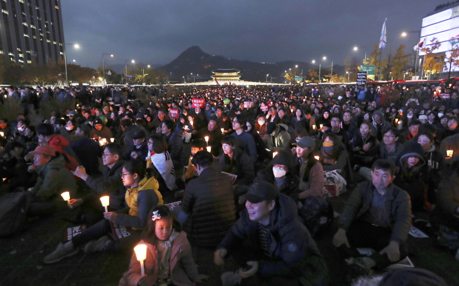 FILE- In this Saturday, Nov. 12, 2016, file photo, South Korean protesters hold up candles during a rally calling for South Korean President Park Geun-hye to step down in Seoul, South Korea. Tens, and possibly hundreds, of thousands of South Koreans marched in Seoul on Saturday demanding the ouster of President Park Geun-hye in one of the biggest protests in the country since its democratization about 30 years ago.