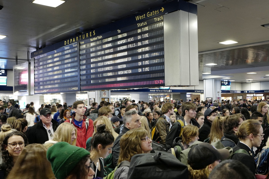 Passengers stand beneath an electronic signboard in New York&#039;s Penn Station as they wait to board a train, Sunday, Nov. 27, 2016. Millions of Americans are returning home Sundy after the long Thanksgiving weekend.
