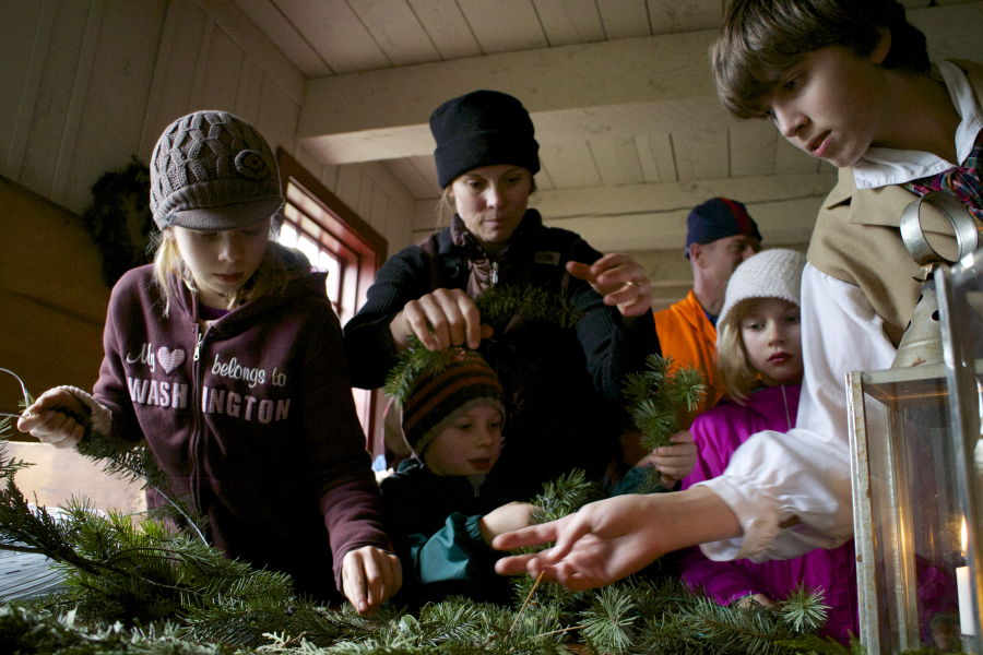 The Gilliland family of Woodland -- Noel, from left, William, Kathleen and Charlee -- get help from a re-enactor as they make wreaths during the 2013 Christmas at Fort Vancouver event.