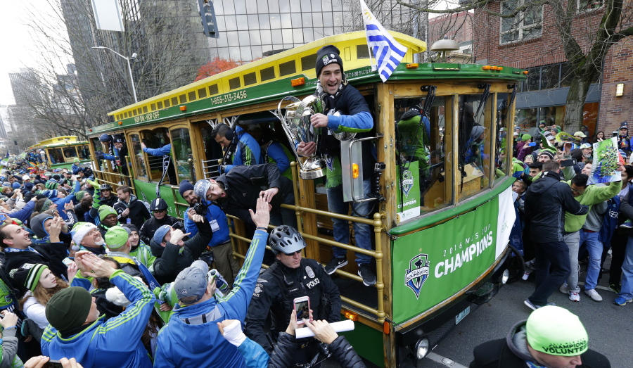 In this Dec. 13, 2016 file photo, Seattle Sounders forward Nicolas Lodeiro, center, holds the MLS Cup trophy for fans to touch as he rides a trolly with teammates during a championship celebration march in Seattle. The Sounders championship was among the top news stories in Washington state in 2016. (AP Photo/Ted S. Warren, File) (Photos by Ted S.